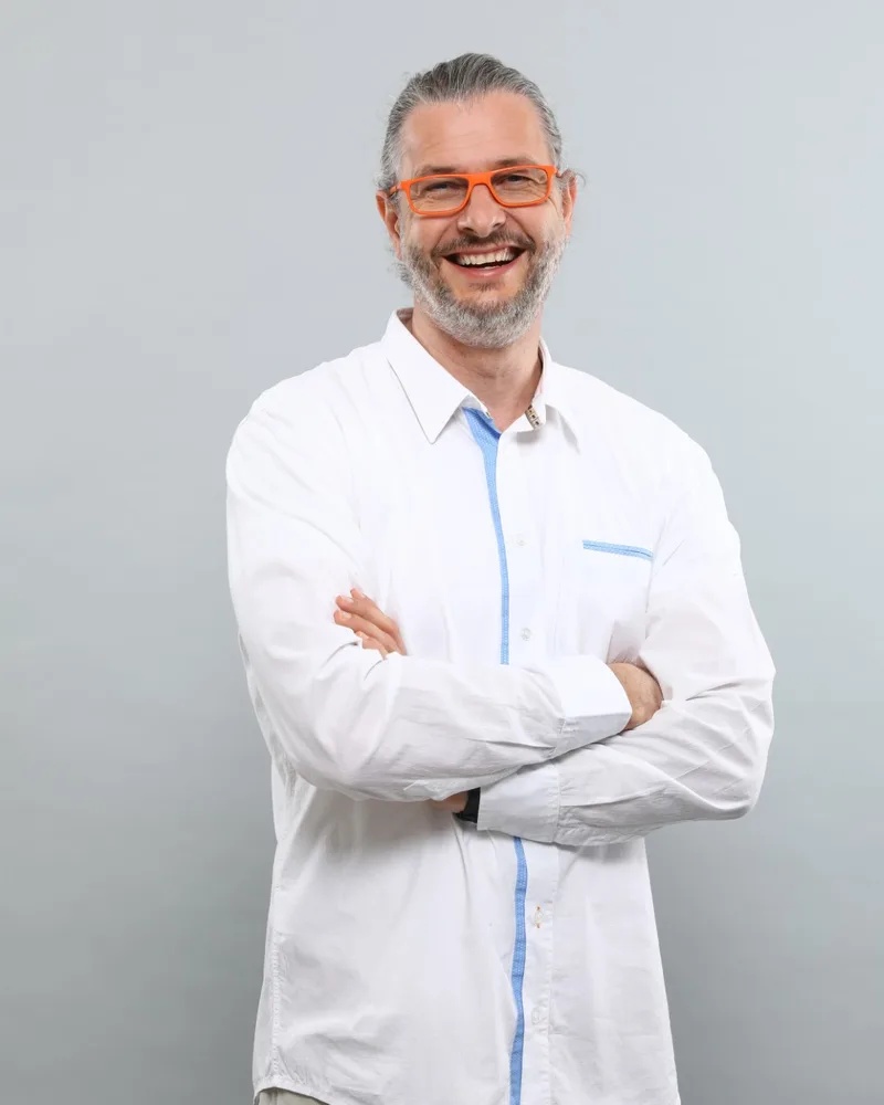 Stefan Heinemann, Webentwickler aus Potsdam, mit verschränkten Armen und orangefarbener Brille